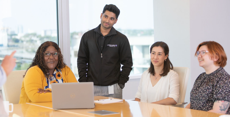 BOYNECLARKE team members chat and smile together in a bright office space.