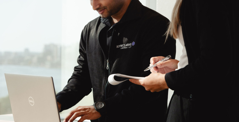 BOYNECLARKE colleagues review notes together using a laptop and a clipboard.